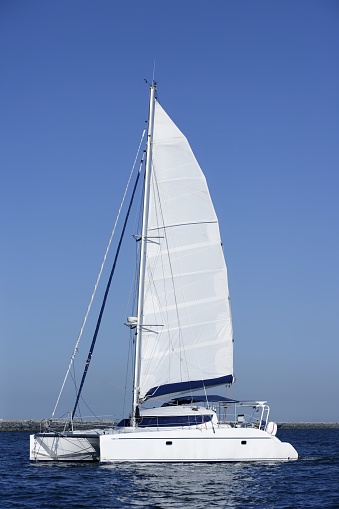 Catamaran sailboat sailing blue ocean water on summer day