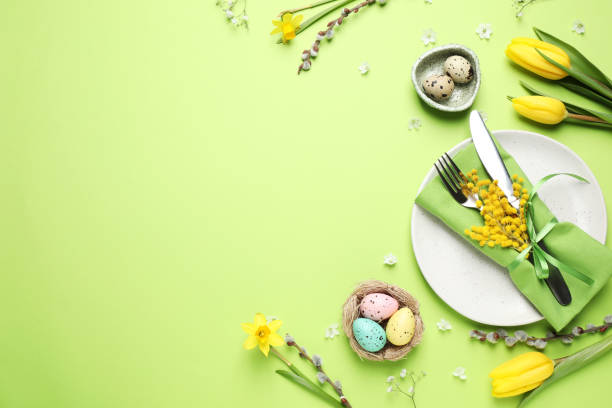 istock Festive Easter table setting with eggs and floral decor on green background, flat lay. Space for text 1336273475
