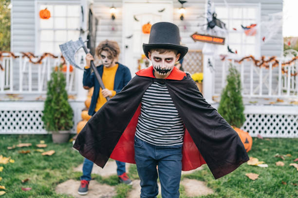 Boys dressed in Halloween costumes trick or treating at night during Halloween
