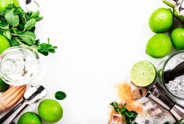 istock Mojito cocktail making. Mint, lime, ice, white rum, cane sugar - ingredients and bar utensils. Top view, white background. Flat lay 1336275250
