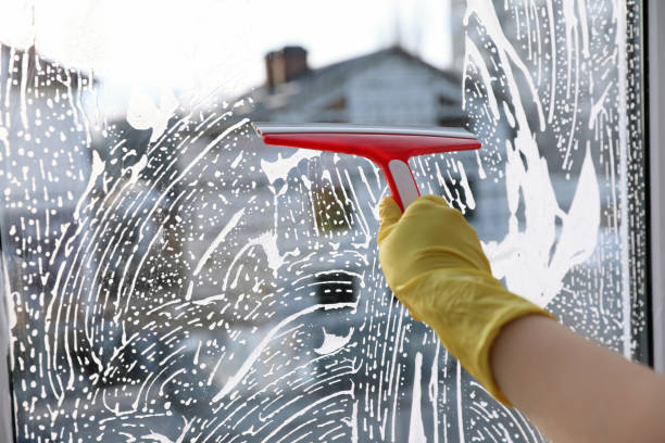 istock Woman cleaning window with squeegee indoors, closeup 1336275399