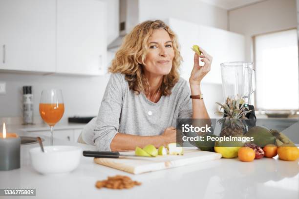 Shot Of A Woman Preparing And Eating Fruit Before Making A Smoothie Stock Photo - Download Image Now