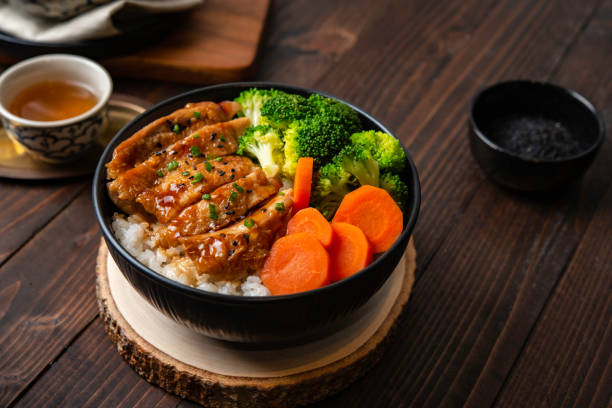 japanese food style : homemade chicken teriyaki grilled with rice , carrot , broccoli put on the black bowl and place on wooden table - teriyaki broccoli carrot chicken imagens e fotografias de stock