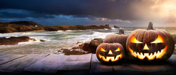 istock Halloween lanterns at sunset on a wood tabletop at the coast. 1336281023