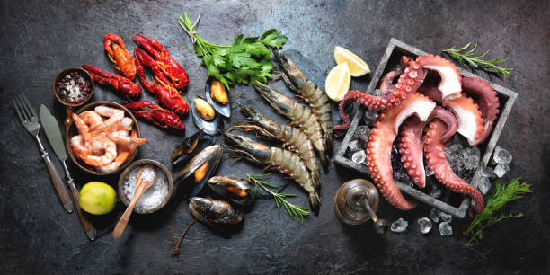 Variety of fresh delicious seafood Variety of fresh delicious seafood. Octopus tentacles, black tiger shrimps, king prawn and mussels with fresh herbs and seasoning on black rustic background crustacean stock pictures, royalty-free photos & images