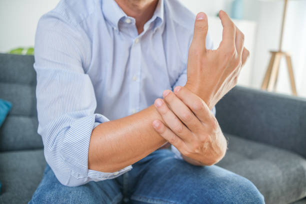 istock Man suffering from wrist pain seated on the sofa 1336283041