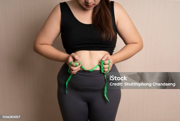 Beautiful Fat Woman In Sportswear Catches Her Big Belly Or Belly Fat With Tape Measure Healthy Weight Control Concept Overweight Bloated Belly Stock Photo - Download Image Now