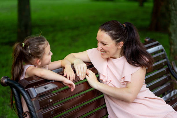 母と娘は、夏に公園を歩いて5-6歳、ベンチに座って娘に話し、幸せな家族の概念、母子の関係 - 35 40 years women female smiling ストックフォトと画像