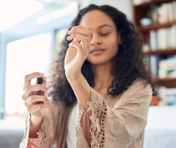 Shot of an attractive young woman standing alone at home and spraying perfume in the morning This is my favourite scent perfume stock pictures, royalty-free photos & images