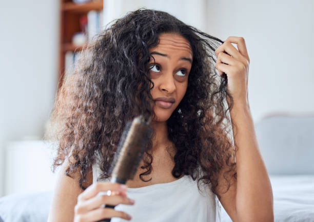 Shot of an attractive young woman standing alone at home and brushing her curly hair in the morning Urgh, what am I going to do with you? frizzy stock pictures, royalty-free photos & images