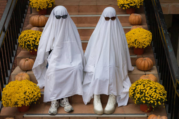 trendy entertainment is to dress in white bedspreads or sheets symbolically depicting ghosts. ghost challenge - material data sheets imagens e fotografias de stock