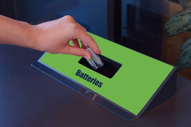 Womans hand throws the batteries into a special trash can for the separate collection of hazardous waste