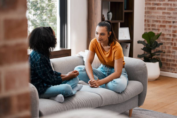 foto de una joven madre e hija hablando mientras están sentadas en el sofá de casa - women sofa teenage girls hairstyle fotografías e imágenes de stock