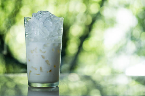 istock Fresh milk with ice in glass against nature background 1336298980