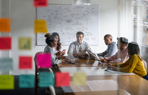 Group of Latin American people in a meeting discussing a business plan - shot through glass