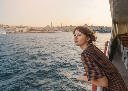 Young Caucasian woman traveling on ferry through Bosphorus in Istanbul in summer
