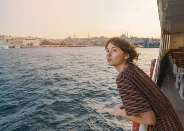 Young Caucasian woman traveling on ferry through Bosphorus in Istanbul in summer