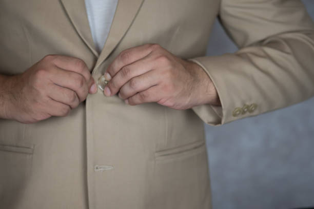 istock Man is buttoning the buttons on the cream suit. Getting ready for formal event. 1336299650