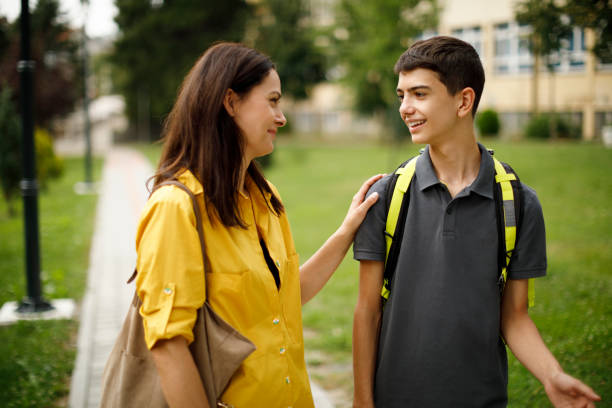 mother and teenage boy in front of school - mãe filho conversa imagens e fotografias de stock