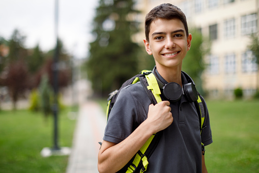 Portrait of smiling teenage boy in front of the school