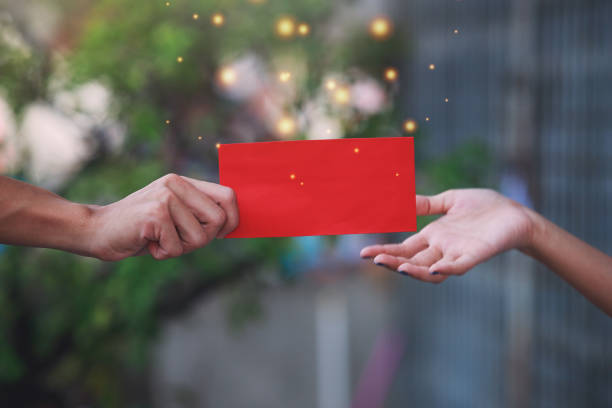 The elders hand give red envelope "Ang pao" to their children and grandchildren. Concept to celebrate Chinese New Year. stock photo