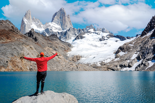 a young man standing with open arms and staring to monte fits roy and laguna de los tres happy