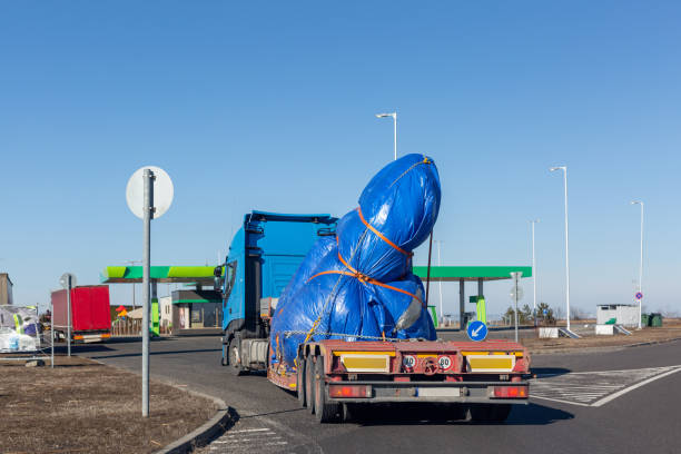 istock Blue truck with special semi-trailer for oversized loads transportation. Oversize load on flatbed trailer 1336314973
