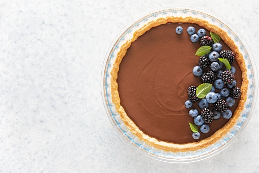 Dark chocolate mousse tart decorated with fresh blueberries and the mint, view from above, copy space for a text