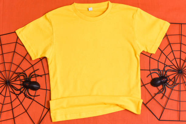 istock Yellow t-shirt mockup with halloween spiderweb decor on orange background 1336318498