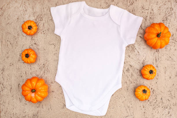 istock White baby bodysuit mockup with halloween decor on gold 1336318499