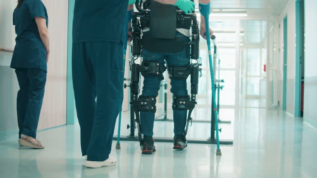 Medical workers are helping a patient to walk in the exosuit