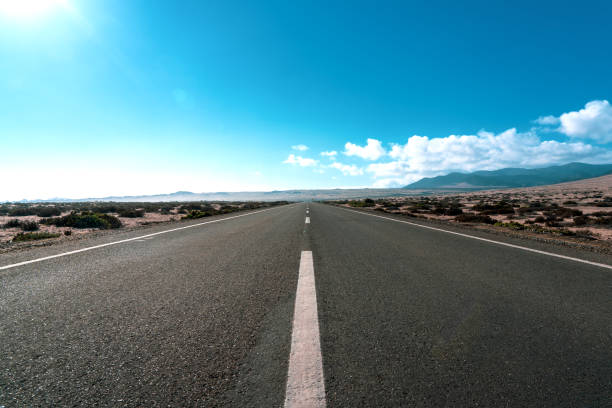 strada nel deserto - arid climate asphalt barren blue foto e immagini stock