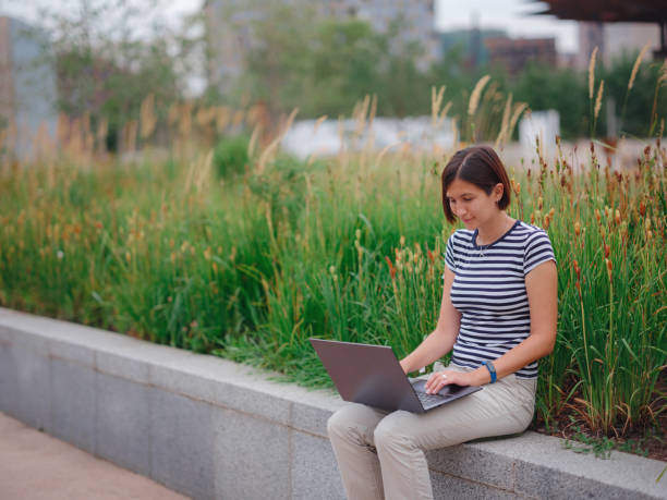 istock woman working with laptop in modern university campus park. 1336320813