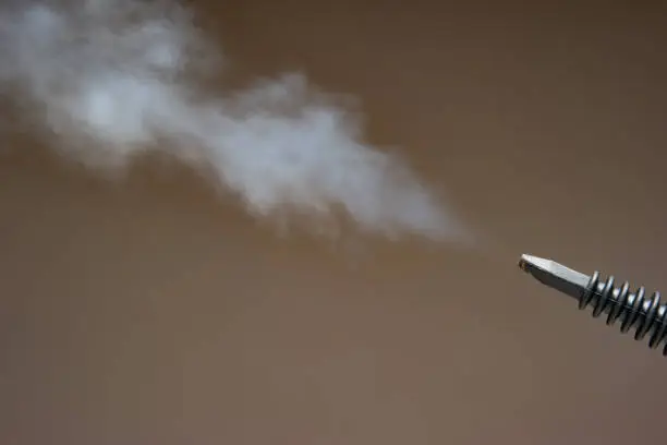 Steam pressure cleaner plastic nozzle spraying water vapor cloud. Close up studio shot, no people.