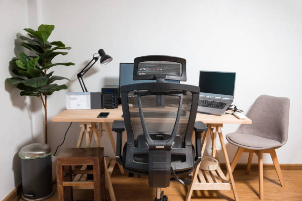 istock Wooden desk with laptop, display, mouse, lamp, ergonomic chair and artificial tree in workplace on bedroom 1336323080