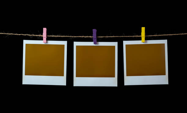 Blank square photo frames hanging on a clothesline with black background