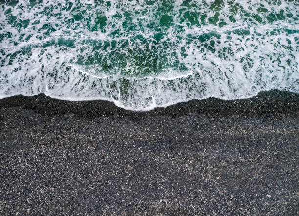 istock Sea waves breaking on a shore with volcanic black sand, background with copy space 1336323240