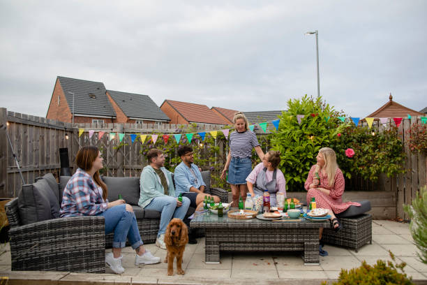 Enjoying a BBQ Party Group of friends having a bbq social gathering outdoors in the North East of England. They are sitting together sharing food on an outdoor patio and there is also a cocker spaniel with them. outdoor dining photos stock pictures, royalty-free photos & images