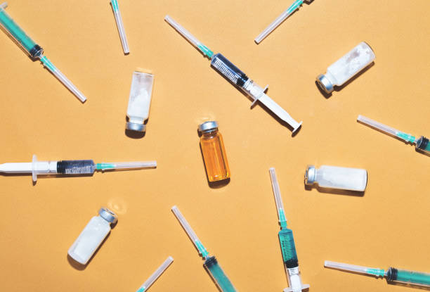spritzen werden mit injektions- und medizinischen impfstoffflaschen auf gelbem hintergrund gefüllt. draufsicht - botox injection stock-fotos und bilder