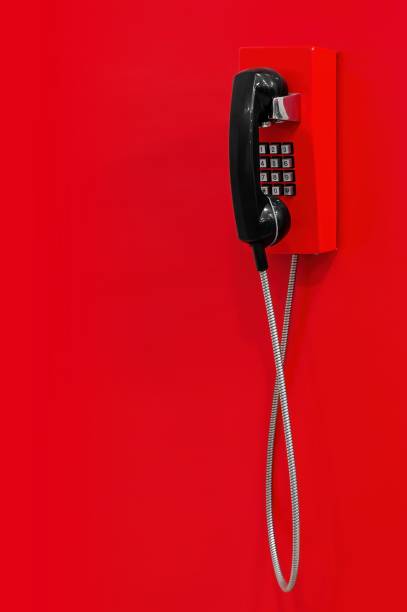 Red wall telephone (taxophone) on red background. Emergency call to 112, 911,  fire and rescue, medic, police, urgent message. stock photo