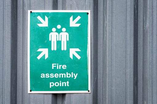 An outdoor emergency safety sign, guiding people on the location to meet in the event of a fire evacuation.
