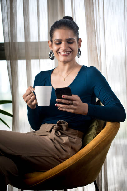 istock Woman drinking coffee and using mobile phone at home 1336333857