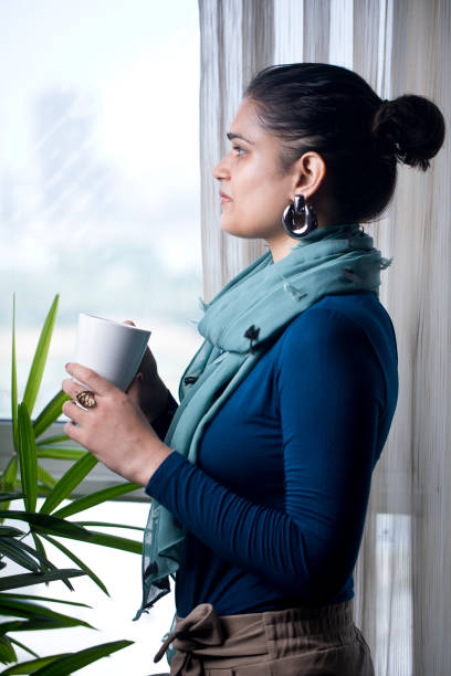 istock Woman drinking coffee and looking out through window 1336333932