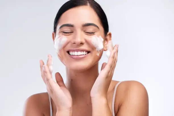 Photo of Studio shot of a beautiful young woman washing her face