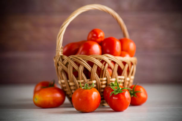 fresh ripe red tomatoes in a basket on a wooden table