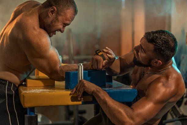 two strong athletes in the gym compete in arm wrestling. bodybuilders armwreslers in athletic training room - wrestling sport two people people imagens e fotografias de stock