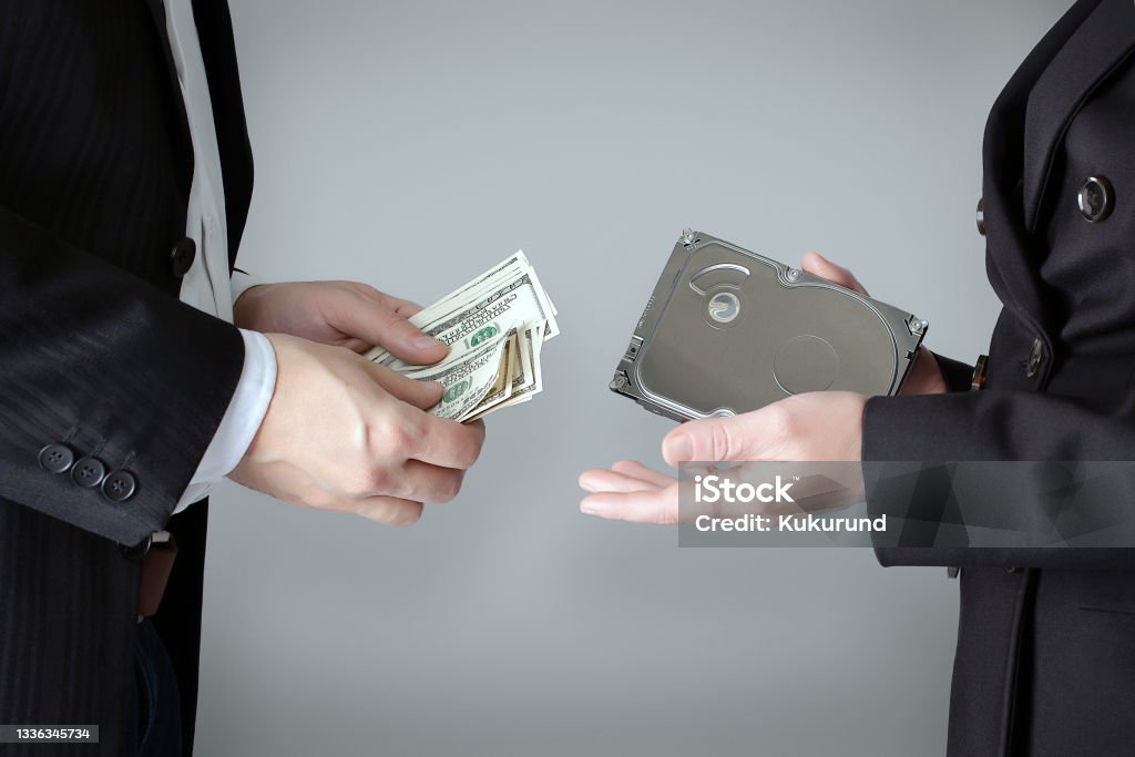 The scene of the crime: selling confidential information on the hard drive of competitors or officials for the wad of bills in U.S. dollars. White (gray) background. Adult Stock Photo
