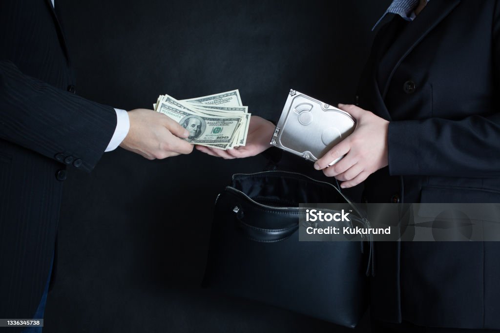 The scene of the crime: selling confidential information on the hard drive of competitors or officials for the wad of bills in U.S. dollars. Black background. Adult Stock Photo