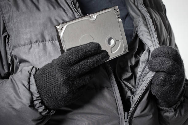 el ciber ladrón con guantes negros esconde un disco duro robado con información de datos corporativos o secretos - clutch disk fotografías e imágenes de stock