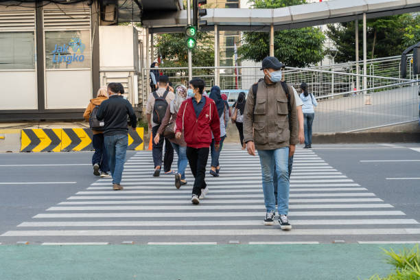 people waiting for a green traffic light to cross the road safely - voetgangersstoplicht stockfoto's en -beelden